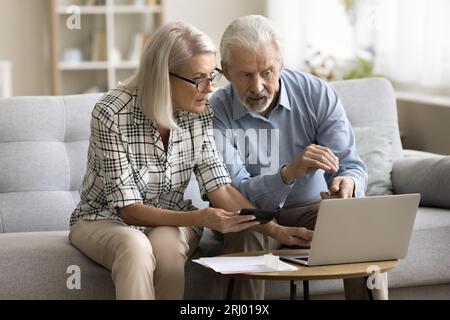 Serious senior married couple calculating domestic expenses Stock Photo