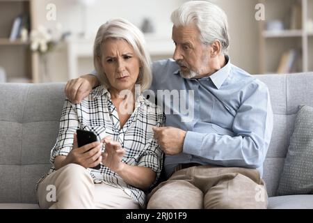 Anxious concerned older couple using mobile phone together Stock Photo