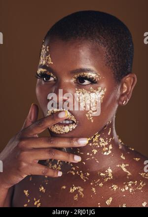 Gold, Glitter Portrait And Black Woman Beauty With Makeup And Skincare Mask  In Studio With Sparkle Cosmetics. Brown Background, Funny And Model With  Golden Paint For Skin Glow And Creative Shine Stock