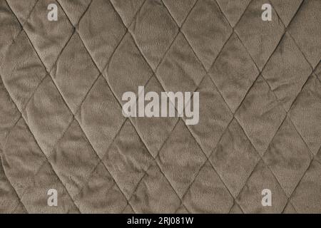 Quilted velours fabric background. Brown texture blanket or puffer jacket, stiched with diamond pattern, soft wrinkled surface, crupmed textile Stock Photo