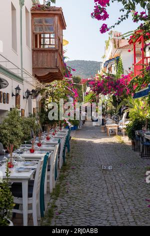 A picturesque traditional narrow street in Kalkan old town with tables laid for evening meals. Kalkan, Turkey Stock Photo