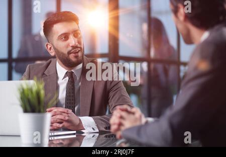 Two medium focused business workers communicate in the office. Stock Photo