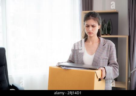 Portrait young woman employee carrying cardboard box or belonging with frustrated and stress while fired from job with despair, businesswoman resign w Stock Photo