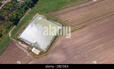 Artificial reservoir for irrigation of crops. View from a drone. Agricultural operation Stock Photo