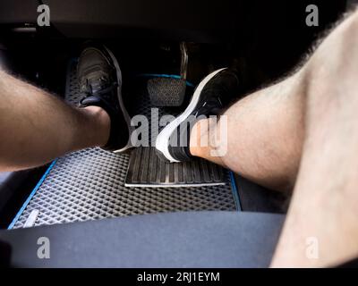 A man's feet put the pedals of the car controls Stock Photo