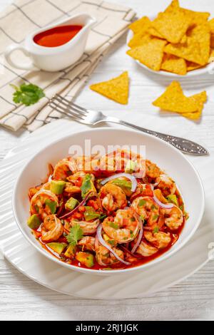 cocktail de camarones, mexican shrimp cocktail salad, chilled appetizer of shrimp, fresh tomato, pepper, avocado, red onion and cilantro in white bowl Stock Photo