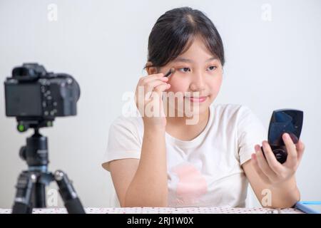 Beauty girl blogger concept, Asian woman draw eyebrows review in live streaming isolated on white background Stock Photo