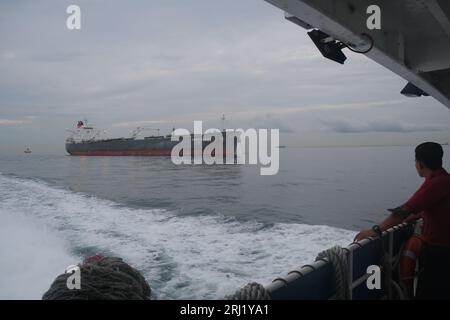 A man on a ferry from Desaru in Malaysia to Singapore looks at a tanker in the Strait of Malacca, one of the world's busiest shipping lanes Stock Photo