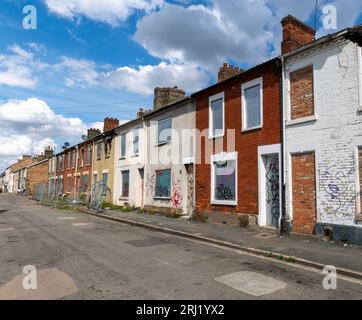 A row of burnt out and derelict terraced houses in the North of England with boarded up windows, doors and fire damaged roofs awaiting demolition Stock Photo