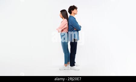 Unhappy Young Couple Crossing Hands Standing Back To Back, Studio Stock Photo