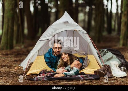 Cheerful young caucasian couple in jackets enjoy travel vacation with tent, sleeping, rest Stock Photo