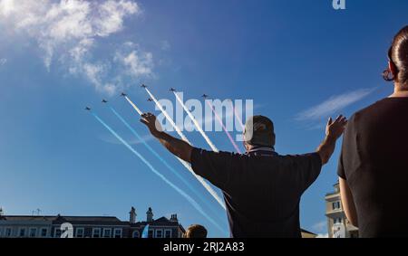 A man on Eastbourne beach stretches out his arms to welcome the world famous RAF display team The Red Arrows as they fly overhead at the annual Eastbo Stock Photo