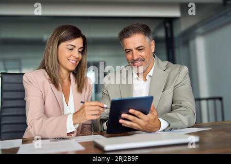 Two professional executives business people talking working on tablet in office. Stock Photo