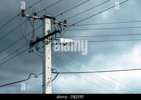 Old power utility and street light pole with cables and wires against dramatic sky, selective focus Stock Photo