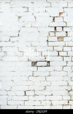 Old damaged brick wall painted in white color, vertical image Stock Photo