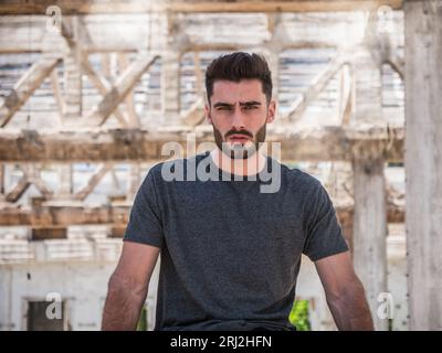 Photo of a man standing in front of a wooden structure Stock Photo