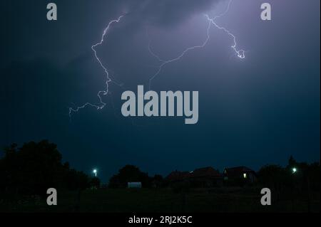 Lightning discharge high in the sky during a severe nighttime thunderstorm Stock Photo