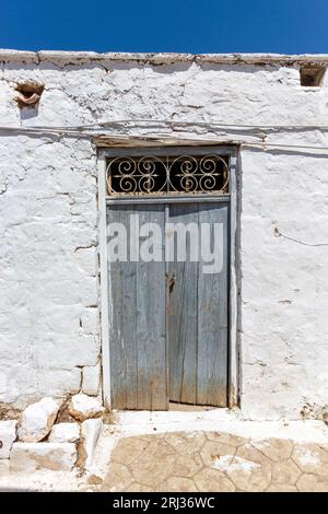 Traditional old wooden door of a typical house with white washed walls in the Old Town of Aegina island, in Saronic Gulf near Athens, Greece, Europe. Stock Photo