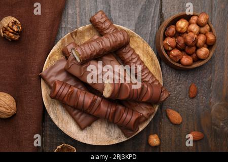 Different tasty chocolate bars and hazelnuts on wooden table, flat lay Stock Photo