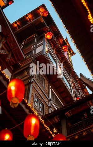 A vibrant display of multicolored lights and paper lanterns hangs from a building facade, casting a warm glow over the surrounding city Stock Photo