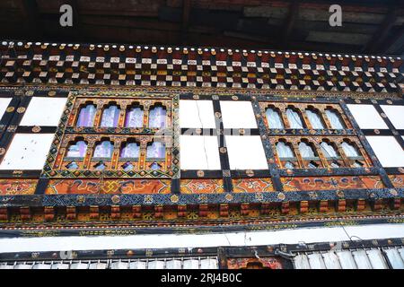 Typical Bhutanese architecture featuring intricately painted woodwork, banks of ornate windows and whitewashed stone masonry at Punakha Dzong, Bhutan Stock Photo