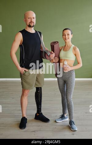 Portrait of sportive young couple working out indoors with man with prosthetic leg looking at camera Stock Photo