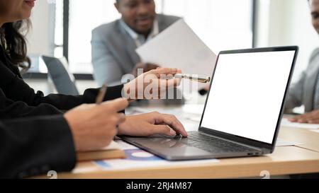 Close-up image of a professional senior Asian businesswoman using her laptop during the meeting with her team. Laptop white screen mockup Stock Photo
