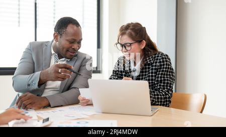 A beautiful young Asian businesswoman is discussing project details with an African American boss during the meeting. Diverse businesspeople Stock Photo