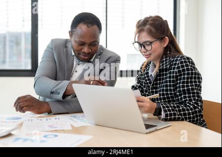 A beautiful young Asian businesswoman is discussing project details with an African American boss during the meeting. Diverse businesspeople Stock Photo