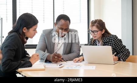 A professional and smart African American male boss is co-working with Asian employees, and analyzing and planning financial plan with his team during Stock Photo