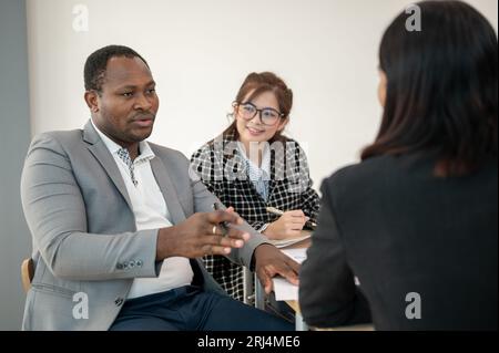 A professional and smart African American male boss is co-working with Asian employees, and giving a new project to his team during the meeting. A mul Stock Photo