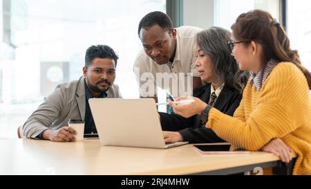 A professional African American businessman is working with his Asian colleagues, planning and brainstorming a new project in the meeting room togethe Stock Photo