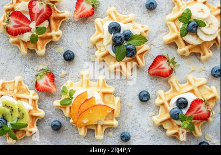 Freshly baked waffles with strawberries and blueberries on a concrete gray background.  Homemade baking. Stock Photo