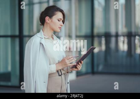 Portrait of smart caucasian young entrepreneur fashion woman using her digital tablet while standing in the office building Stock Photo