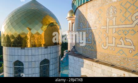 Almaty, Kazakhstan - August 17, 2023: Prayer on the wall of the dome near the minaret. Arabic mosaic Stock Photo