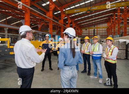 Warehouse safety meeting, people with hard hats. Industrial teamwork. Stock Photo