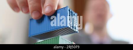 Business man arranging stack of freight containers on his table in office. Stock Photo