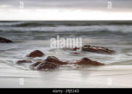 Waves breaking over rocks slow shutterspeed tilt-shift landscape photography Stock Photo