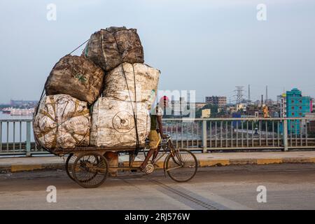 A rickshaw van transporting used plastic bottles to a plastic recycling center on the Bangladesh-Chaina Friendship Bridge over the Buriganga River. Dh Stock Photo