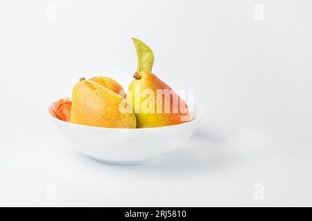 Three ripe pears on a plate against a white background Stock Photo