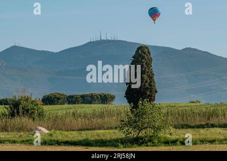 A colorful hot air balloon flies over Monte Serra and the countryside near Pisa, Italy Stock Photo