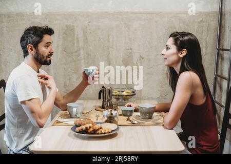 Young happy couple in love having breakfast at the kitchen table Stock Photo