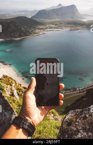Man's hand holding a cellphone to take a picture of a scenic view Stock Photo