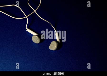 Wired ear bud head set on a blue table cloth surface Stock Photo