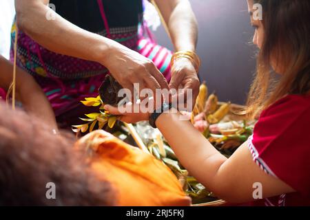 Karen traditional wrist tying ceremony: Tying white and red cotton threads on their wrist. One of the most famous event. Stock Photo