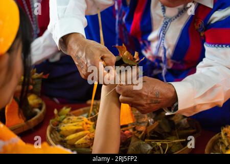 Karen traditional wrist tying ceremony: Tying white and red cotton threads on their wrist. One of the most famous event. Stock Photo