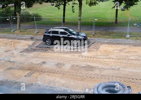 Car standing on an island of brick amidst a broken up road with only sand Stock Photo