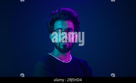 Portrait Indian serious man developer coding worker programmer profile looking to side turn head internet technology hacker male in glasses in blue Stock Photo