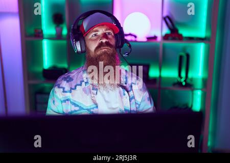 Young redhead man streamer playing video game using computer at gaming room Stock Photo