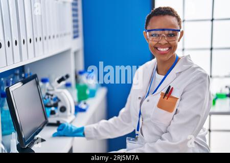 African american woman scientist smiling confident using computer at laboratory Stock Photo
